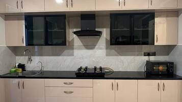 A modern kitchen with beige cabinets, a black countertop, and a marble floor.