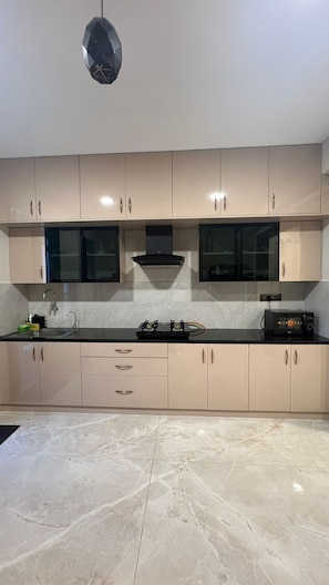 Een moderne keuken met beige kastjes, een zwart aanrecht en een marmeren vloer.