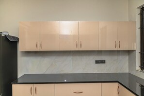 A kitchen with beige cabinets, a black countertop, and a marble backsplash. - Aureum Park Residence Spacious Family-Friendly 3BHK Near CBD & MG Road (Bengaluru)