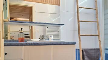 Een badkamer met een houten wastafelmeubel, een spiegel, een handdoekhouder en een blauwe betegelde vloer.