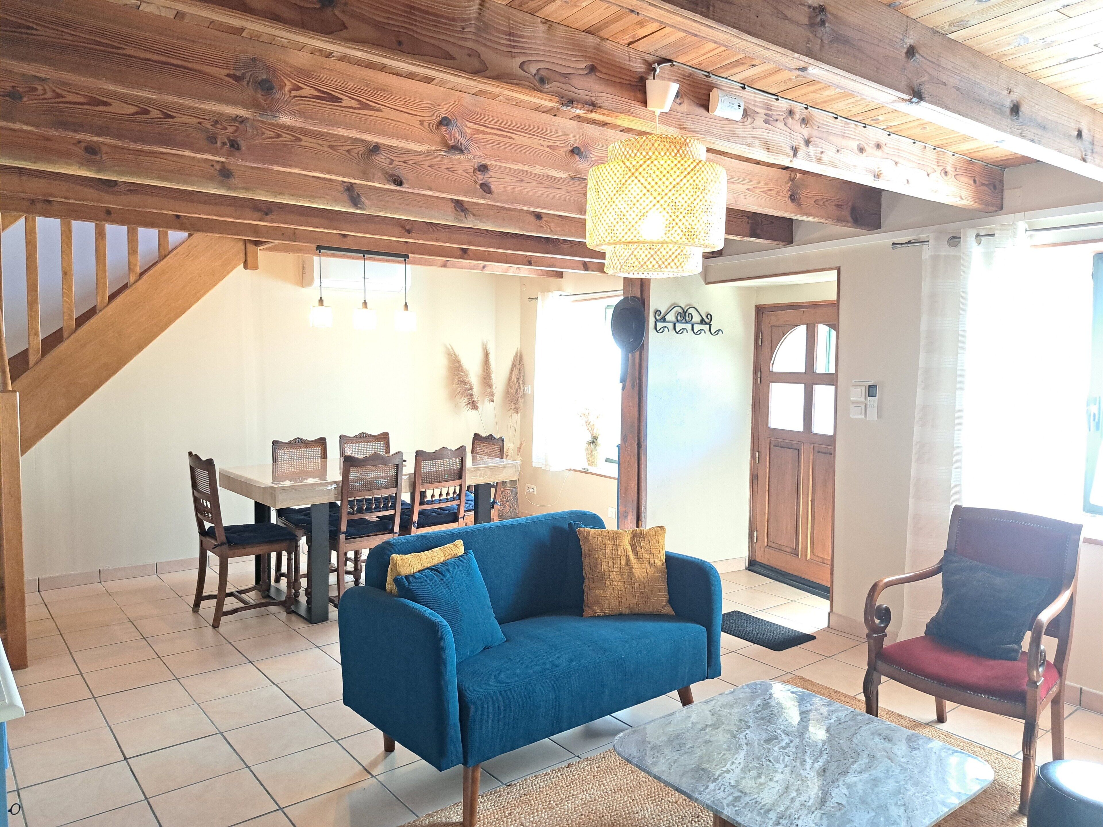 A living room with a blue sofa, a coffee table, and a dining area with a table and chairs.