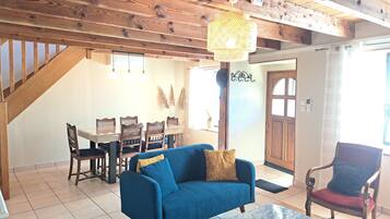 Una sala de estar con un sofá azul, una mesa de centro y un comedor con mesa y sillas.