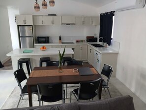 Un ambiente compatto con angolo cottura, zona pranzo e divano.