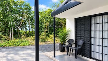 A modern outdoor seating area with a pergola, two chairs, and a potted plant.
