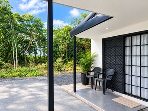 Un'area salotto esterna moderna con una pergola, due sedie e una pianta in vaso.