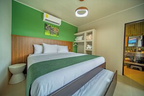 Hotellihuone, jossa on sänky, wc, peilillä varustettu pesuallas ja vihreä seinä.