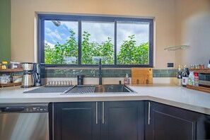 Eine moderne Küche mit großem Fenster, integriertem Spülbecken und verschiedenen Geräten.