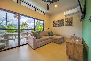 A modern living room with a sofa, a wooden cabinet, and a dining area with a table and chairs. - Casa Nantú - Arenal Volcano Views • Zero-Entry Pool • Sauna • 4BR/4.5BA (La Fortuna)