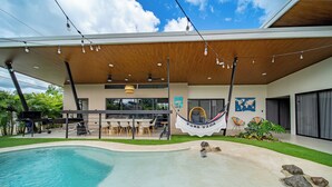 A modern outdoor pool area with a hammock, seating, and a view of the surrounding landscape. - Casa Nantú - Arenal Volcano Views • Zero-Entry Pool • Sauna • 4BR/4.5BA (La Fortuna)