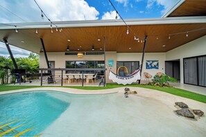 Ein moderner Poolbereich im Freien mit einer Hängematte, Sitzgelegenheiten und Blick auf die umliegende Landschaft.