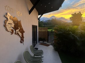 A modern patio with a map of Costa Rica, outdoor seating, and a view of a mountain range. - Casa Nantú - Arenal Volcano Views • Zero-Entry Pool • Sauna • 4BR/4.5BA (La Fortuna)