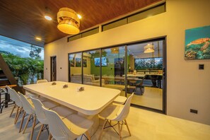 Un comedor moderno con una larga mesa y sillas, ventanas amplias y vistas al exterior.