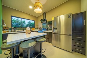 Una cocina moderna con una isla central, electrodomésticos de acero inoxidable y un amplio ventanal.