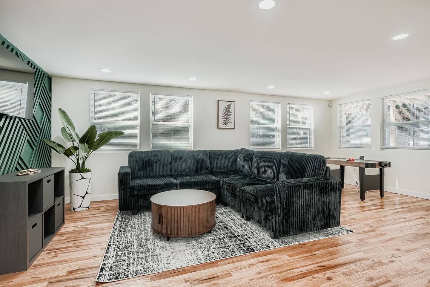 A modern living room with a sectional sofa, a coffee table, a TV, and a plant.