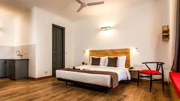A hotel room with a bed, a desk, a chair, and a ceiling fan.