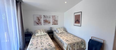Un dormitorio con dos camas, una mesita de noche, una lámpara y un cuadro en la pared.