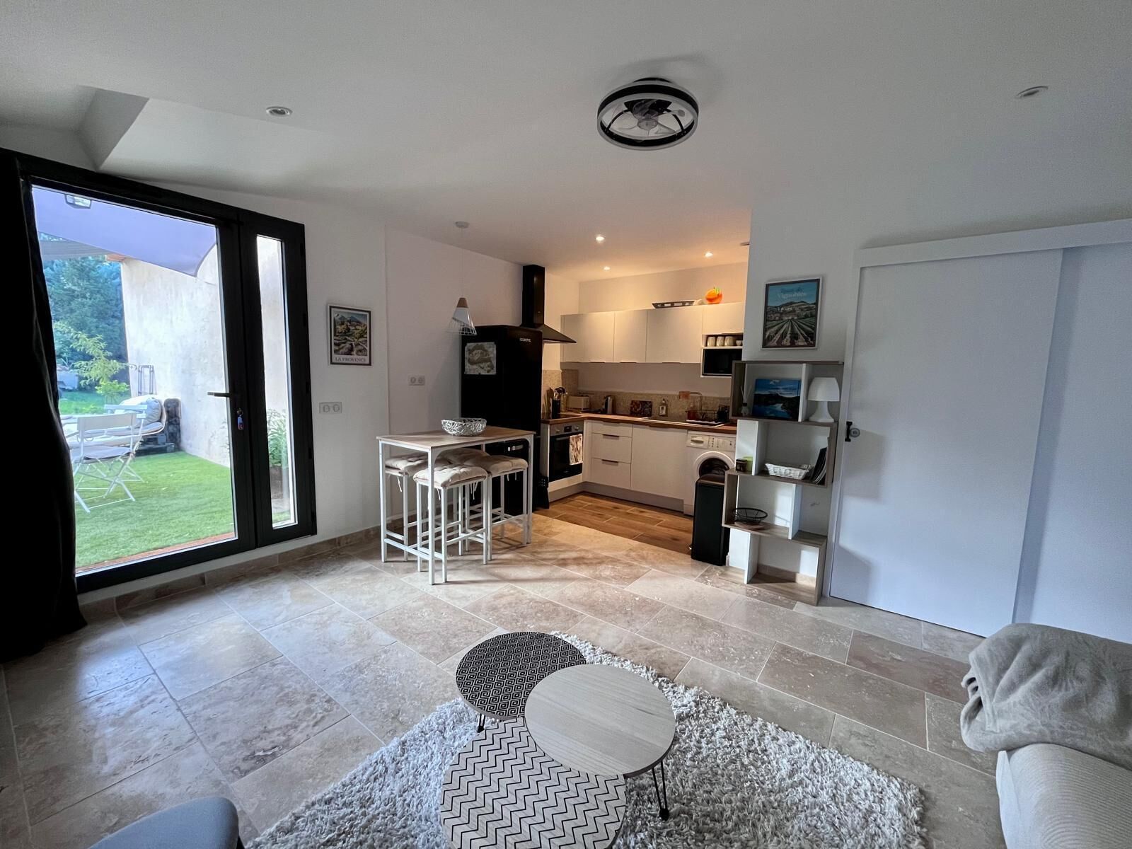 Een compacte woonruimte met een keuken, een eethoek en een schuifdeur naar een tuin.