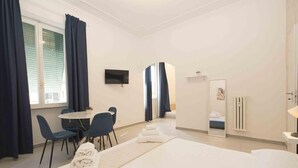 Ein Hotelzimmer mit einem Bett, einem Schreibtisch, zwei Stühlen, einem Fernseher und einem Spiegel.