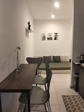 A compact living space with a dining table, chairs, a sofa, and a small kitchen area. - Metanoia Stays Prati (Rome)