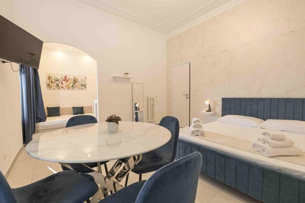 Une chambre d’hôtel comprenant un lit, une table de salle à manger ronde avec des chaises, un canapé, un téléviseur et une œuvre d’art accrochée au mur.
