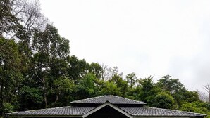 A traditional building with a tiled roof, a central entrance, and a surrounding grassy area.