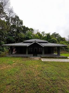 A traditional building with a tiled roof, a central entrance, and a surrounding grassy area. - Hills and Chills Nature Stay (Sakleshpur)