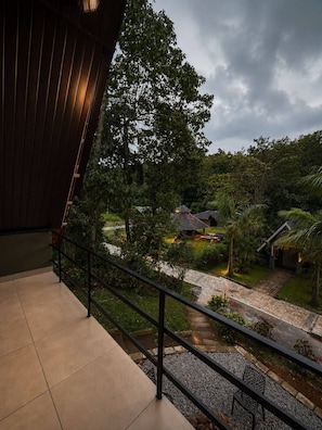 A balcony with a view of a garden and a house. - Hills and Chills Nature Stay (Sakleshpur)