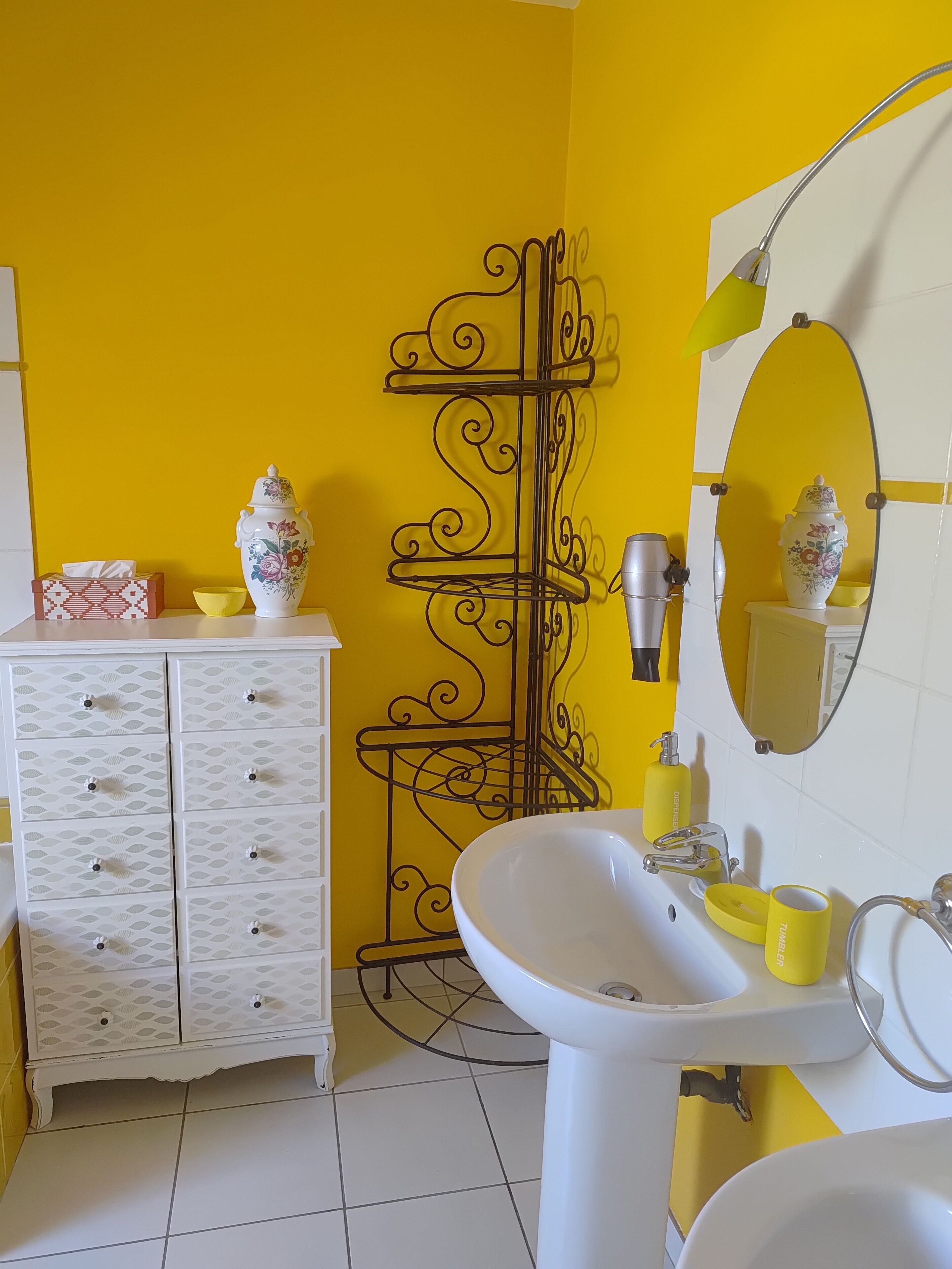 A bathroom with a white vanity, a mirror, a sink, and a yellow wall.