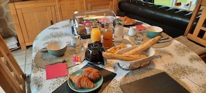A breakfast setting with croissants, a coffee pot, and various beverages on a table. - "Marine" Room (La Fresnais)