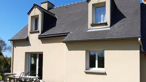 Ein zweistöckiges Haus mit flachem Dach, Schornstein und Satellitenschüssel.