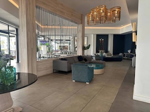 A spacious lobby with a seating area, a large window, and a modern chandelier. - Luxurious 2-bedroom Apartment in Pretoria With Pool Access (Pretoria)