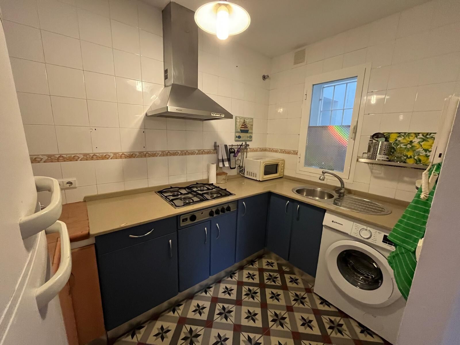 Une cuisine compacte équipée d’une cuisinière à gaz, d’un four à micro-ondes, d’un évier et d’un lave-linge.