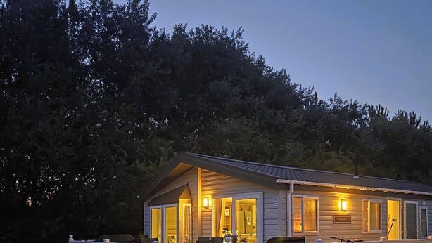 A single-story cabin with a porch, surrounded by trees.