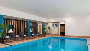 Una piscina con sillas de descanso y un mural de peces en la pared.