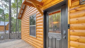 A log cabin with a wooden deck and a dark front door. - Fern and Timber (Murphy)