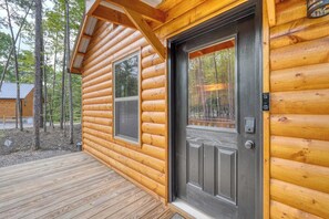 A log cabin with a wooden deck and a dark front door. - Fern and Timber (Murphy)