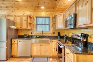 A kitchen with wooden cabinets, a stainless steel refrigerator, a microwave, a stove, and a sink. - Fern and Timber (Murphy)