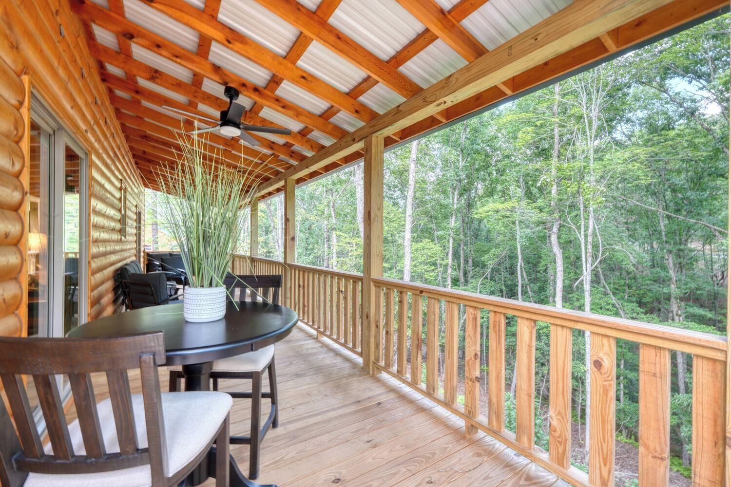 Eine Holzterrasse mit Tisch und Stühlen mit Blick auf ein bewaldetes Gebiet.