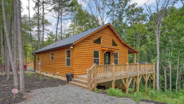 A log cabin with a deck, surrounded by trees. - Fern and Timber (Murphy)