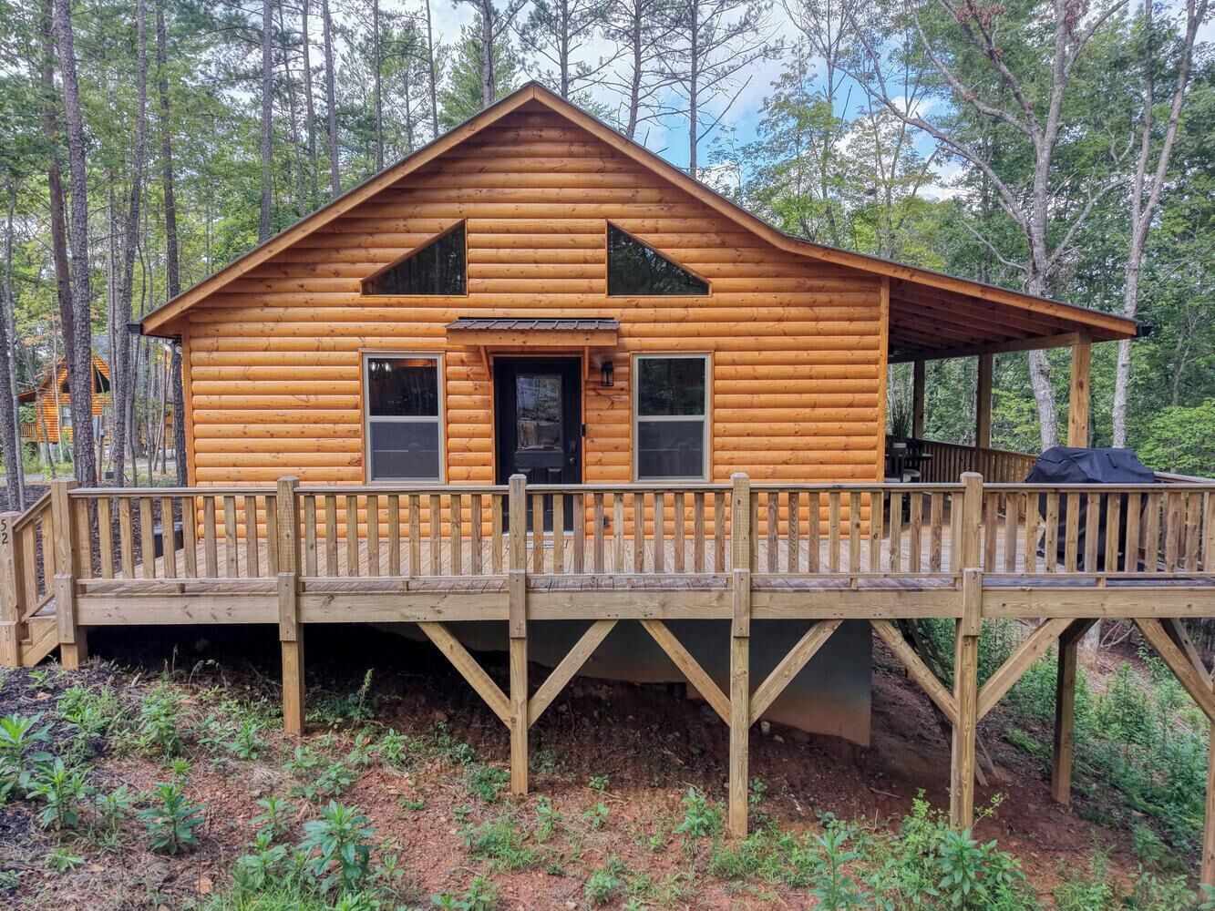 Une cabane en bois dotée d’une terrasse, entourée d’arbres.
