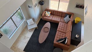 A high-ceiling living room with a sectional sofa, a small round table, and a black rug. - ASU Parent, Alumni, Sports Fan, Traveler - this is your place. (Tempe)