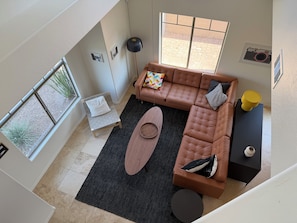 A high-ceiling living room with a sectional sofa, a small round table, and a black rug. - ASU Parent, Alumni, Sports Fan, Traveler - this is your place. (Tempe)