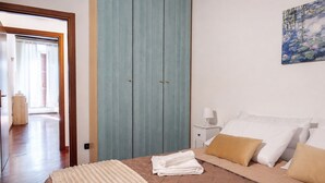 A bedroom with a bed, pillows, a bedside table, a nightstand, a wardrobe, and a painting on the wall. - [Historic Center] Elegant one-bedroom apartment with a balcony (Brescia)