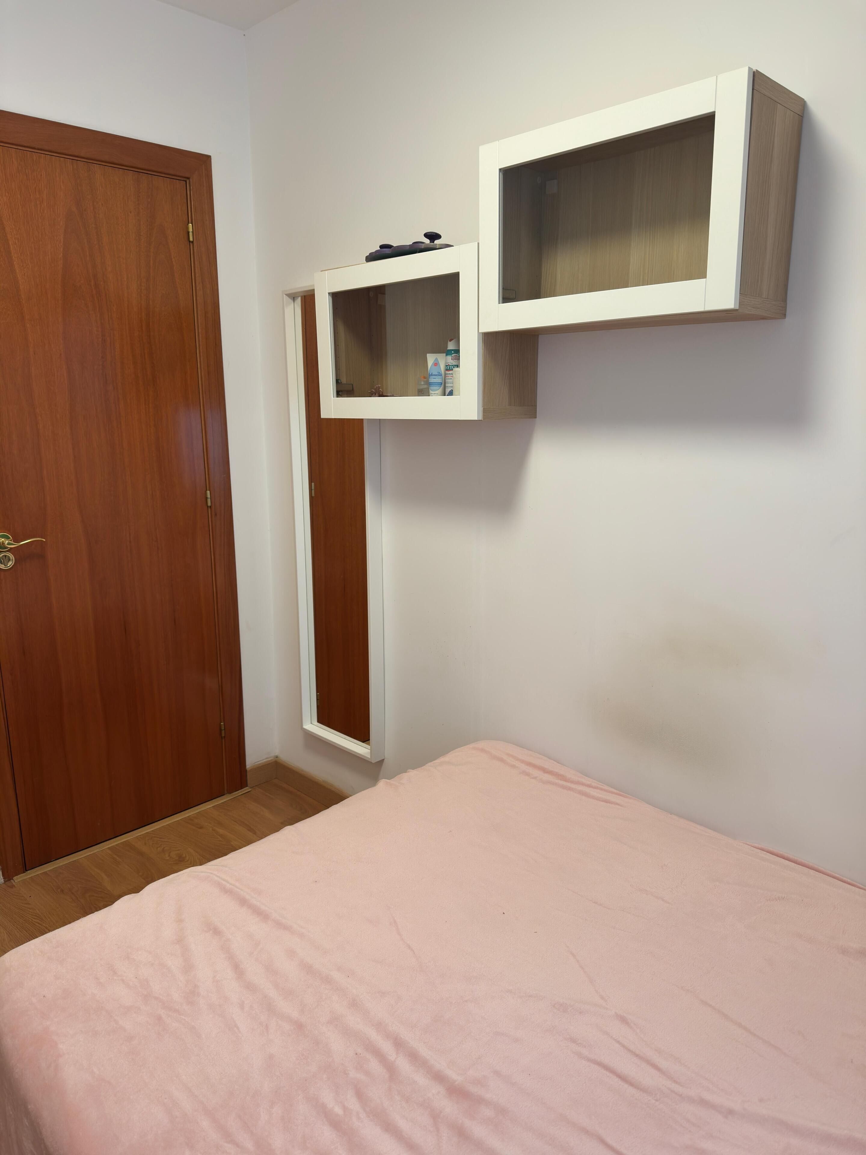 Une pièce comprenant un lit, une armoire en bois et un meuble blanc avec une étagère.