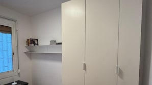 A bedroom with a bed, a wardrobe, a shelf with books, and a desk with a lamp. - Barcelona Room – Temporary Sublet €40/day: 10% discount for longer stays (Spain)
