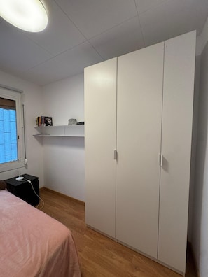 A bedroom with a bed, a wardrobe, a shelf with books, and a desk with a lamp. - Barcelona Room – Temporary Sublet €40/day: 10% discount for longer stays (Spain)
