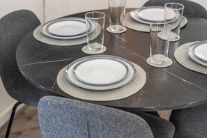 A round dining table with plates, glasses, and a placemat. - 2 Bed Duplex | Jewellery Quarter | Sleeps 4 (West Midlands)