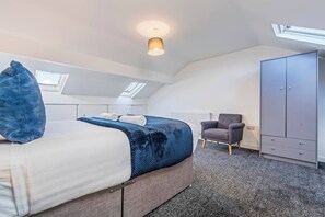 Ein Schlafzimmer mit einem Bett, einem Sessel, einem Kleiderschrank und einem Oberlicht.