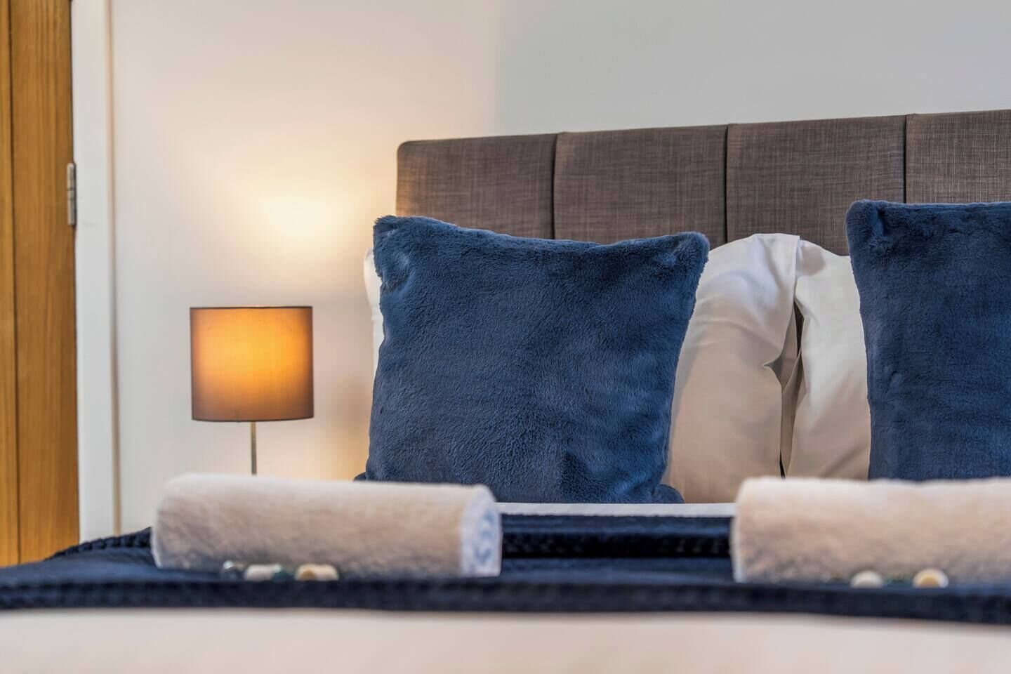 A hotel room with a bed, two pillows, a bedside lamp, and a towel.