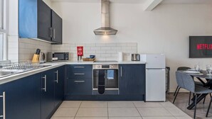 Eine moderne Küche mit dunklen Schränken, einer Edelstahl-Dunstabzugshaube, einer Mikrowelle, einem Toaster und einem Kühlschrank.
